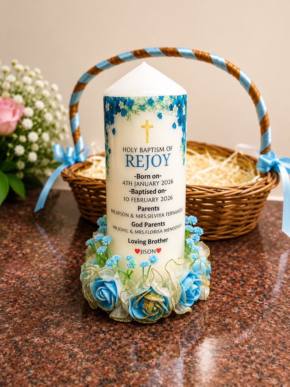 Blue floral baptism candle for Rejoy presented with a ribboned basket