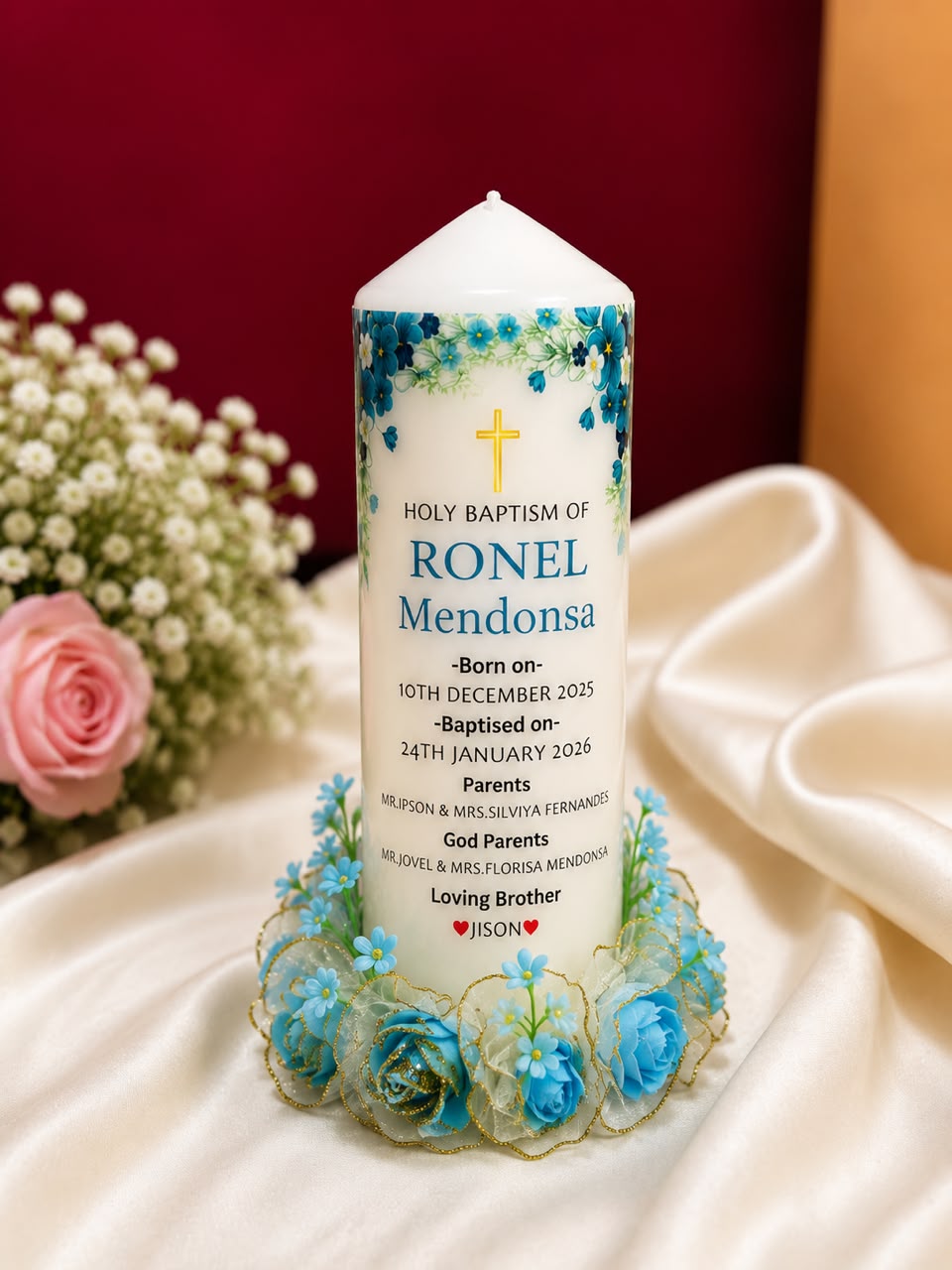 Baptism candle for Ronel Mendonsa with blue roses and family names
