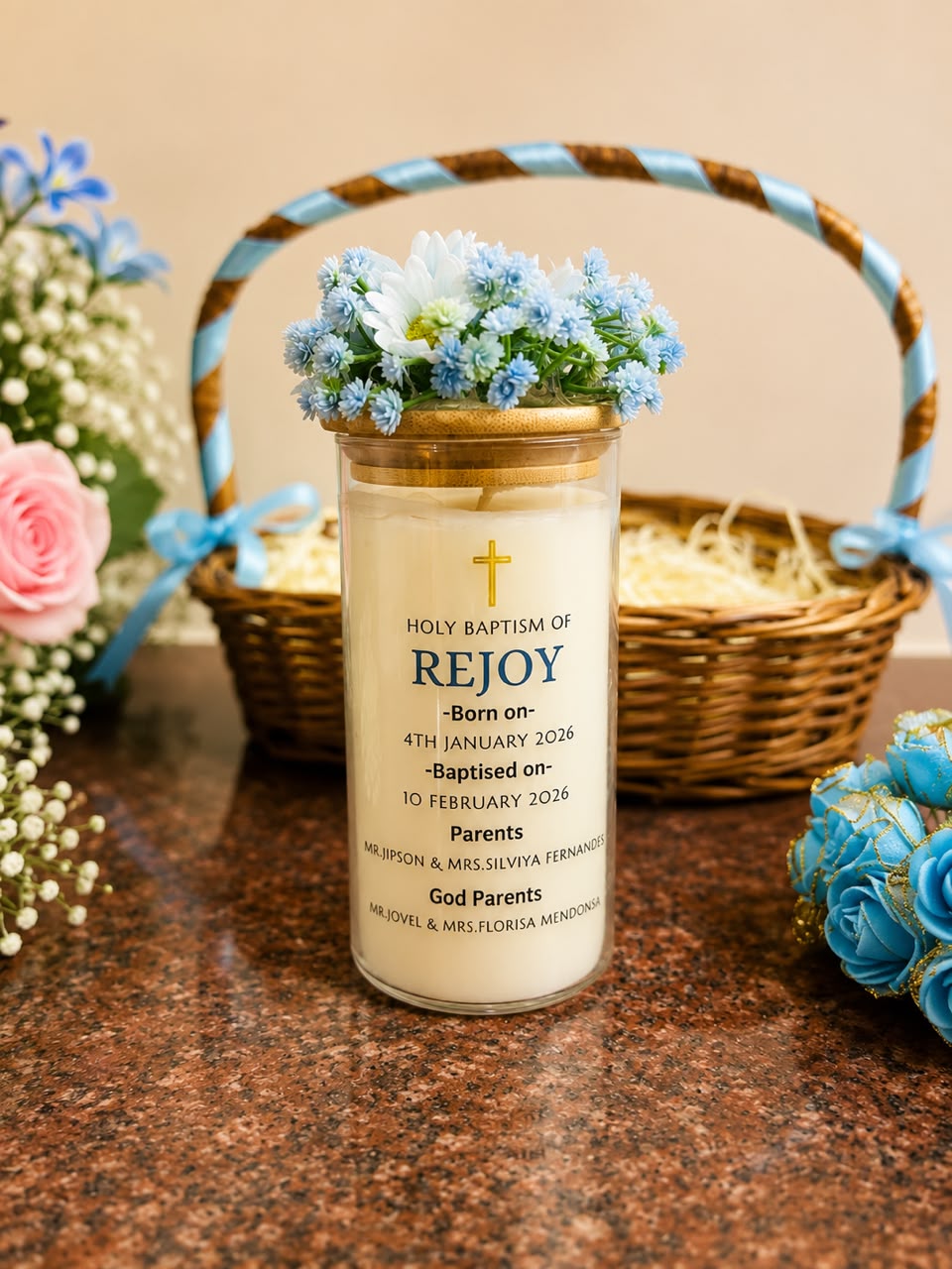 Tall glass jar baptism candle with a bamboo lid and a crown of blue and white flowers